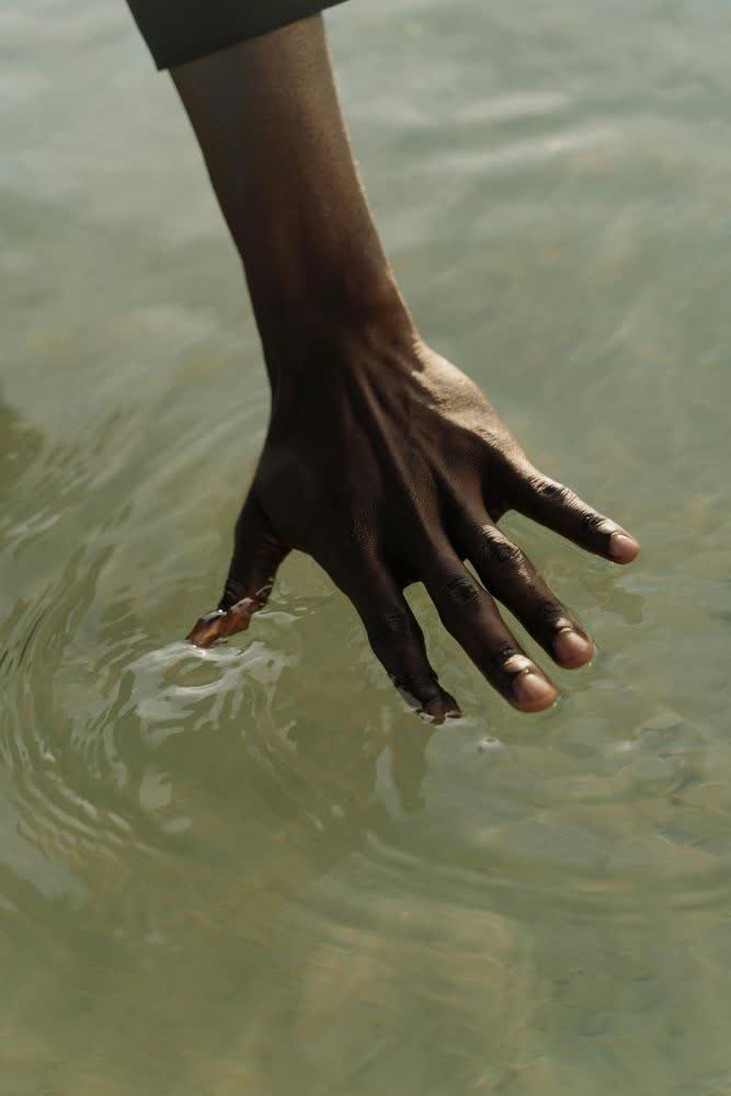 Una mano sfiora l'acqua calma